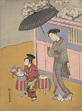 木馬遊びの子供と傘さし美人
